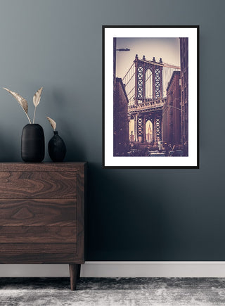 Framed Brooklyn Bridge poster hanging on a dark wall above a wooden dresser in a modern living room.