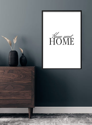 Minimalist "Home sweet Home" poster on a dark wall above a wooden dresser with decor in a modern room.