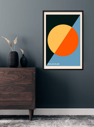 Bauhaus cirkel kunst poster with geometric shapes and bold colors hanging on a dark wall above a wooden dresser.