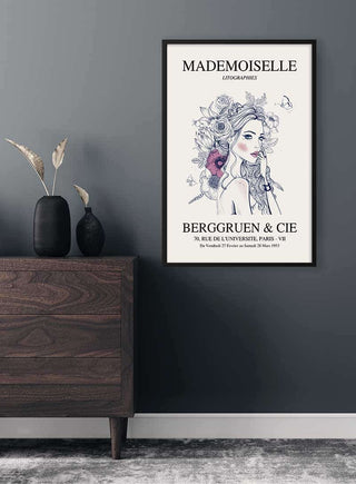 Framed Mademoiselle exhibition #2 poster featuring an illustrated woman, displayed above a dark wooden dresser.