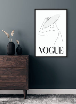 Minimalist black and white Vogue cover poster featuring a woman in a large hat, hung above a wooden dresser.