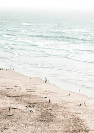 A serene beach scene with gentle waves and people walking along the sandy shore, perfect for coastal decor.