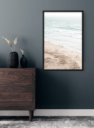 Beach and ocean wall art poster displayed above a wooden dresser in a modern, minimalist room.