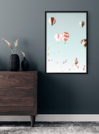 Framed print of colorful hot air balloons floating in a clear sky, displayed on a modern interior wall.