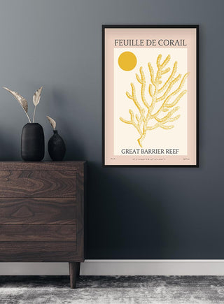 Framed Feuille De Corail No. 06 Plakat featuring yellow coral and sun, displayed above a dark wood dresser.