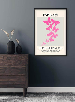 Framed Inspired Papillon No. 06 Plakat featuring pink butterflies, displayed above a wooden dresser in a modern room.