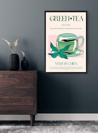 A framed Green Tea No1 poster with a cup of green tea hangs on a wall above a wooden dresser.