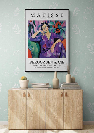 Matisse Purple Madame poster displayed above a wooden cabinet against a light blue patterned wall.