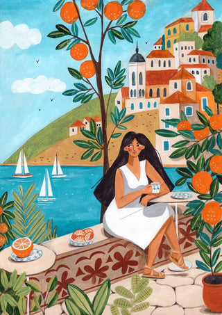 Woman in white dress enjoys coffee by the sea, surrounded by orange trees and Mediterranean coastal houses.