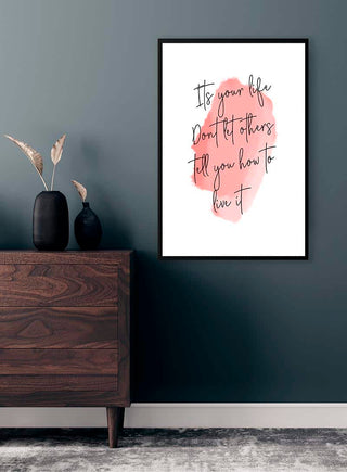 Framed "It's your life" quote poster on a gray wall above wooden dresser with vases.