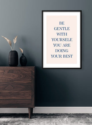 Framed "Be Gentle With Yourself You Are Doing Your Best" print on wall above wooden dresser.