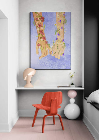 Framed "Holding hands" by Raissa Oltmanns above a modern desk with red chair and decorative items.