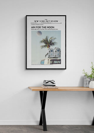 Framed poster titled "The Moon - Art Review Plakat" hanging above a wooden table with decorative items.