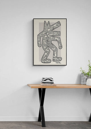 Framed Keith Haring Krokodil artwork hanging above a wooden table with plants and decor items.