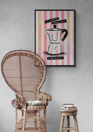 Framed art of moka pot with text "Use napkins, coffee helps, a hug in a cup" on striped background above wicker chair.