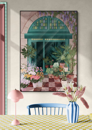 Framed floral artwork of a lush garden scene, displayed above a dining table with fresh flowers in a striped vase.