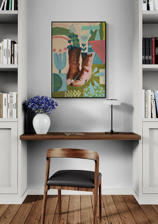 A framed print of "The Boots Are" by Eleanor Baker displayed above a minimalist desk in a modern home office.
