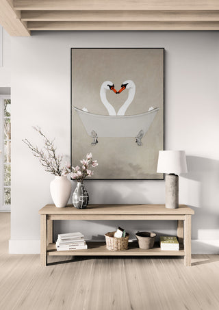 Framed "Swans in Bathtub - Coco de Paris" art above wooden table with vase, lamp, and decor accents.
