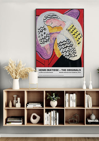 La Rêve ou La Dormeuse art print by Henri Matisse hanging above a modern wooden shelf with books and decor.