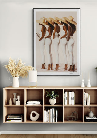 Framed "Ladies" by David Wolf featuring four women in white outfits and hats, displayed above a modern shelf.