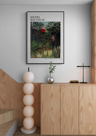 Framed Monkeys And Parrot by Henri Rousseau hanging above a modern wooden cabinet in a minimalist room.