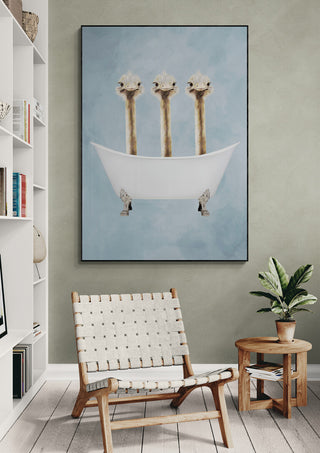 Art print of three ostriches in a bathtub by Coco de Paris displayed on a wall above a modern chair.