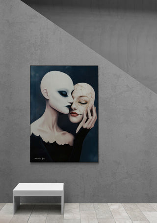 Art print of a masked figure holding a second face, displayed on a minimal gray wall above a white bench.