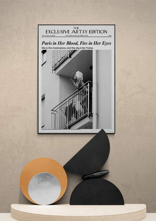 Framed "Paris In Her Blood Artsy Edition" print displayed above modern decorative objects on a neutral shelf.