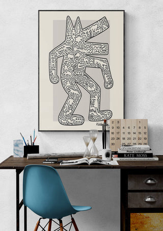 Framed Krokodil artwork by Keith Haring displayed above a modern desk with books and decor items.
