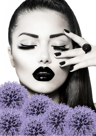 Stylish woman with black lips and nails, posing with hand near face, surrounded by purple flowers.