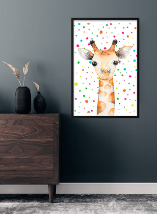 Framed poster of a cute giraffe with colorful dots, hanging on a children's room wall above a wooden dresser.