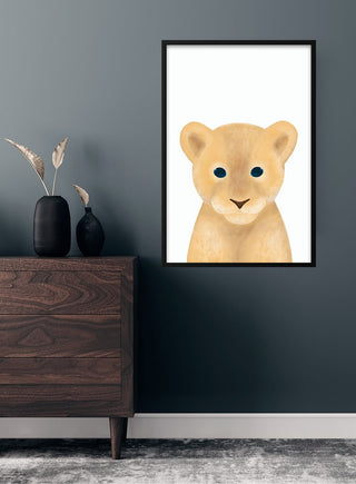 Cute lion cub poster for children displayed on a dark wall above a wooden dresser with vases.