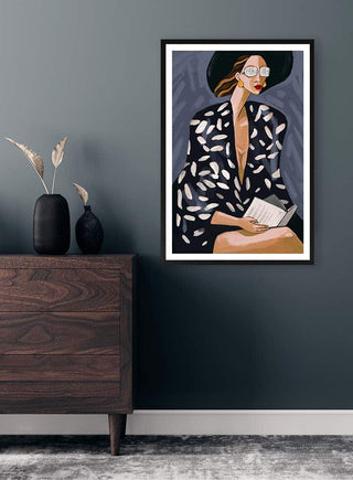 Framed artwork "Cool Readings" by Martina Karlsson displayed on a dark wall above a wooden dresser.