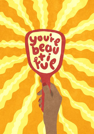 Illustration of a hand holding a mirror with "you're beautiful" and yellow rays in the background.