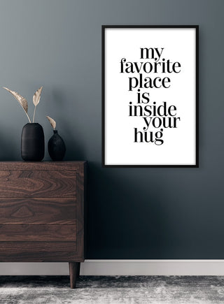 Framed "my favorite place is inside your hug" quote poster on a dark wall above a wooden dresser.