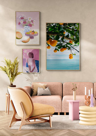 Framed photo of Amalfi Coast oranges hanging above a pink sofa in a modern, stylish living room.