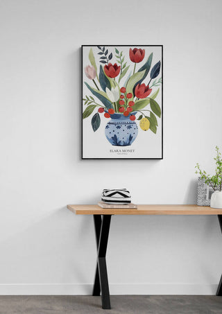 Framed Elara Monet floral art print from Garden of Whimsy hanging above a modern wooden desk.