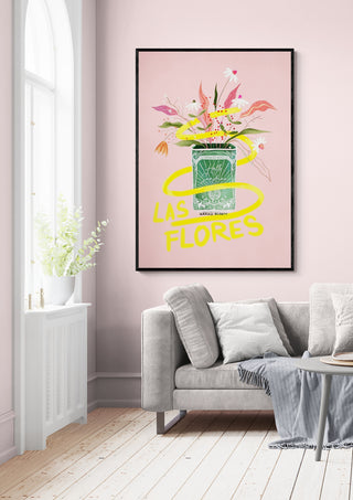 Framed "Las Flores - Baroo Bloom" art print with floral design displayed above a modern gray sofa in a bright room.