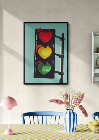 Framed Traffic Light In Love art print with heart-shaped signals, displayed above a dining table in a cozy room.