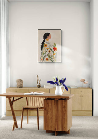 The Enchanted Bloom by Elara Monet framed on a minimalist wall above a wooden desk with floral decor.
