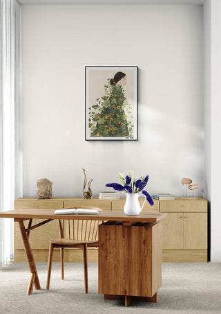 Floral Symphony by Elara Monet framed on a wall above a minimalist wooden desk with a vase of flowers.