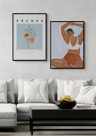 Framed Peaches - Ivy Green art print displayed above a modern sofa with cushions and a black coffee table.