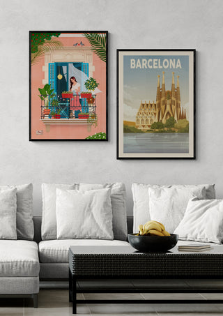 Two framed Barcelona-themed posters above a modern sofa, one of Sagrada Familia and one with local balcony scene.