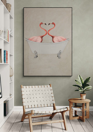 Art print of two flamingos in a bathtub, displayed above a modern chair and small table with a plant.