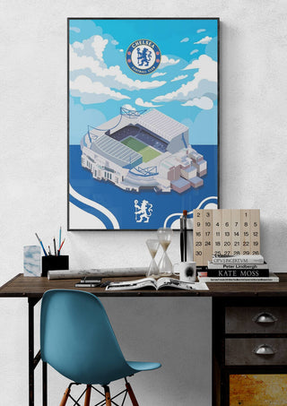 Framed Stamford Bridge Chelsea Football poster displayed above a desk with books and stationery.