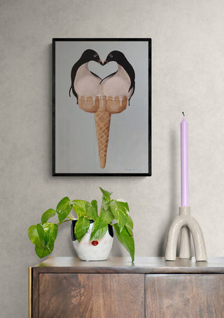 Framed art print of two penguins forming a heart shape above an ice cream cone, displayed on a wall.